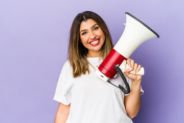 Young indian woman holding a megaphone isolated happy, smiling and cheerful.