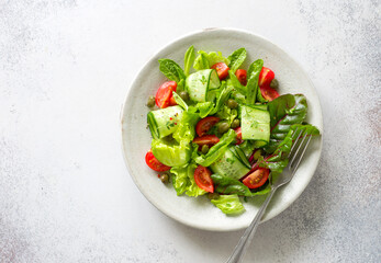 Fresh salad with tomatoes, cucumbers, capers and mixed salad leaves