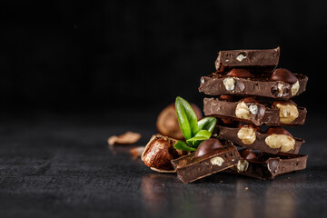 Stack of chocolate slices with mint leaf.Hazelnut and almond milk and dark chocolate pieces tower.Sweet food photo concept. The chunks of broken chocolate