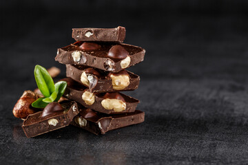 Stack of chocolate slices with mint leaf.Hazelnut and almond milk and dark chocolate pieces tower.Sweet food photo concept. The chunks of broken chocolate