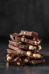 Stack of chocolate slices with mint leaf.Hazelnut and almond milk and dark chocolate pieces tower.Sweet food photo concept. The chunks of broken chocolate