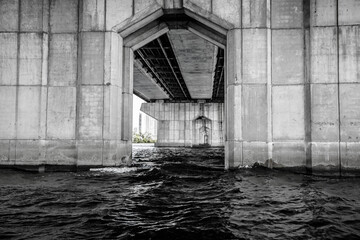 View through the pillars of the bridge. The left bank of the Dnieper in the city of Kiev. Under the bridge. Black and white photo