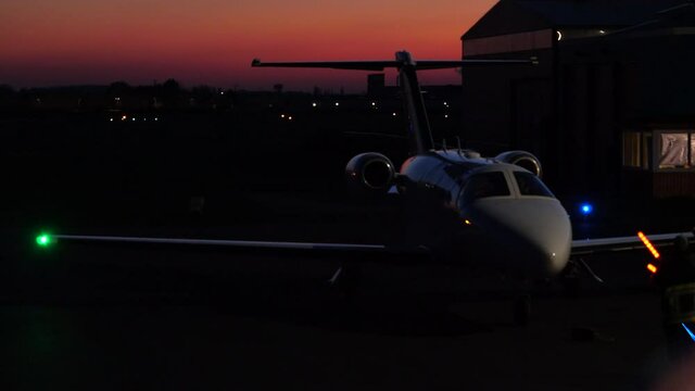 Small Private Jet Being Guided by Marshaller to Parking Spot. Night.