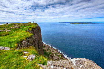 tourist with backpack standing on the cliff Fair Head, Northern Ireland, UK