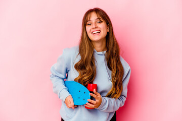 Young skater woman isolated on pink background laughing and having fun.