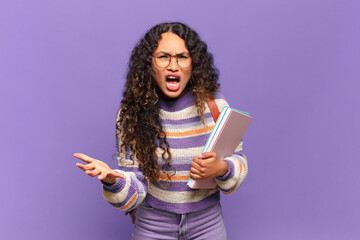 young hispanic woman looking angry, annoyed and frustrated screaming wtf or what’s wrong with...
