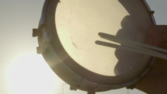 Close-up of playing tambourine against sun with lens flare.