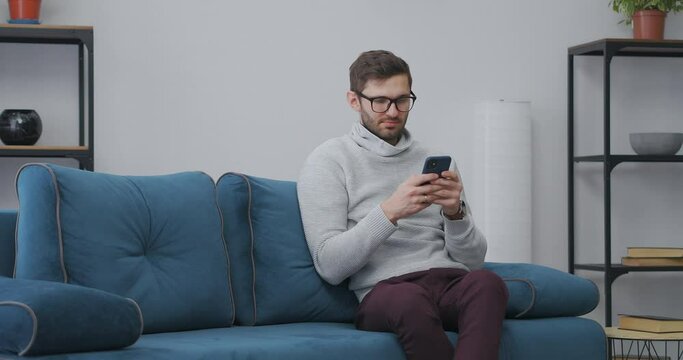 introvert is spending weekend at home, using smartphone, surfing internet, sitting alone on couch in living room