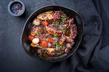 Modern style traditional French coq au vin with vegetable marinated in Burgundy sauce as top view in a design casserole