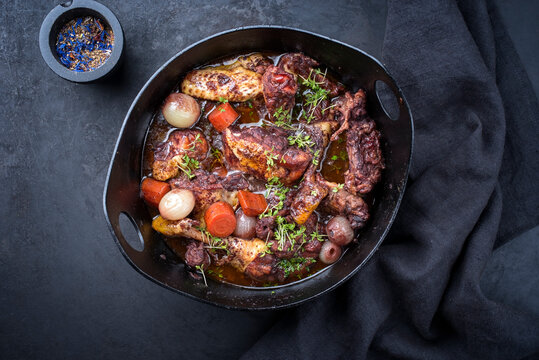 Modern style traditional French coq au vin with vegetable marinated in Burgundy sauce as top view in a design casserole