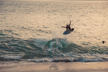 skimboarder jumping in the wave