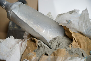 Scoop with cement next to the bag. Preparation of cement and glue mortar
