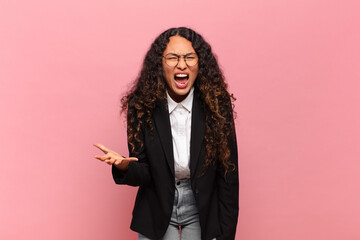 young hispanic woman looking angry, annoyed and frustrated screaming wtf or what’s wrong with...