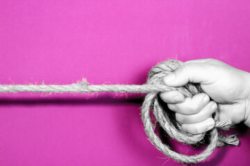 Hand tied with rope on purple background