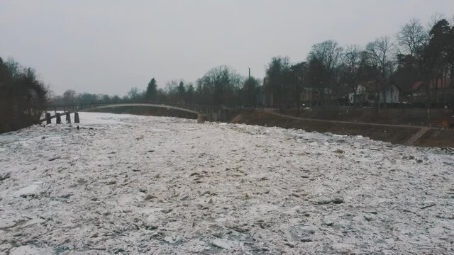 Huge Ice Loads Drift in the River Ogre, Latvia. Aerial Dron Shot in Snowy Mart Day. Congestion on the River in the Spring. A Large Cluster of Moving Ice Blocks