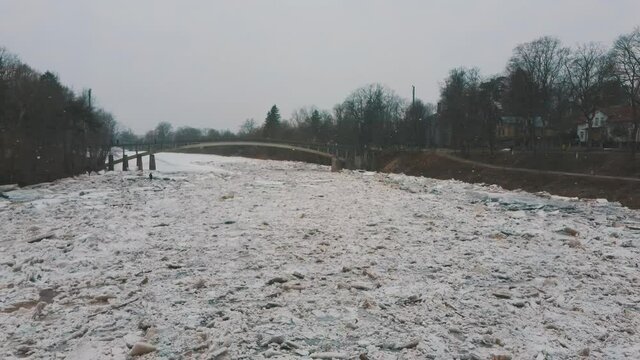 Huge Ice Loads Drift in the River Ogre, Latvia. Aerial Dron Shot in Snowy Mart Day. Congestion on the River in the Spring. A Large Cluster of Moving Ice Blocks