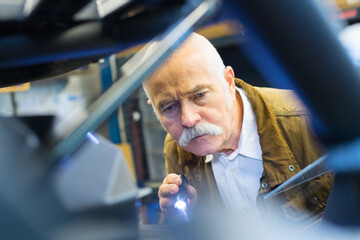 mechanic using torch to inspect vehicle
