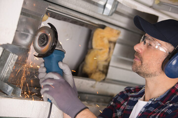 builder using angle grinder and making sparks - obrazy, fototapety, plakaty