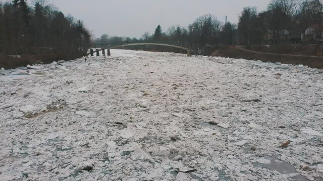 Huge Ice Loads Drift in the River Ogre, Latvia. Aerial Dron Shot in Snowy Mart Day. Congestion on the River in the Spring. A Large Cluster of Moving Ice Blocks