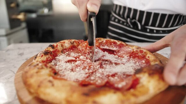 food, culinary, italian cuisine, people and cooking concept - cook hand adding grated cheese to pizza at pizzeria