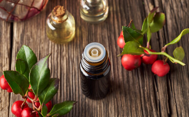 A dark bottle of wintergreen essential oil with wintergreen twigs