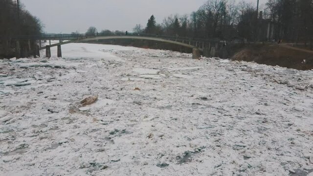Huge Ice Loads Drift in the River Ogre, Latvia. Aerial Dron Shot in Snowy Mart Day. Congestion on the River in the Spring. A Large Cluster of Moving Ice Blocks