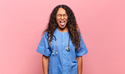 young hispanic woman with cheerful, carefree, rebellious attitude, joking and sticking tongue out,...