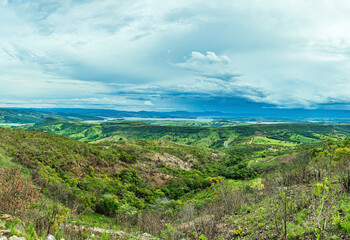 Fototapeta na wymiar Wide panoramic view of nature beauties of Minas Gerais state. Vast green area with a mountainous terrain and the Lake of Furnas on background. Capitólio MG, Brazil.