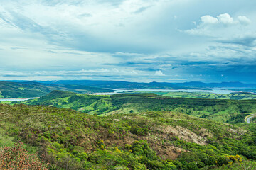Wide panoramic view of nature beauties of Minas Gerais state. Vast green area with 
a mountainous terrain and the Lake of Furnas on background. Capitólio MG, Brazil.