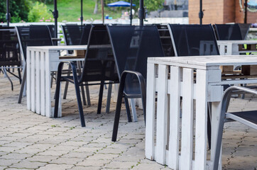 Outdoor cafe interior in the street, with wooden furniture, rotan chairs and creative wooden pallet tables. Selective focus.