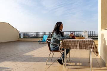 Relaxed woman sitting in her terrace at home and using her mobile phone.