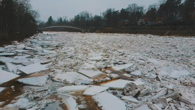 Huge Ice Loads Drift in the River Ogre, Latvia. Aerial Dron Shot in Snowy Mart Day. Congestion on the River in the Spring. A Large Cluster of Moving Ice Blocks