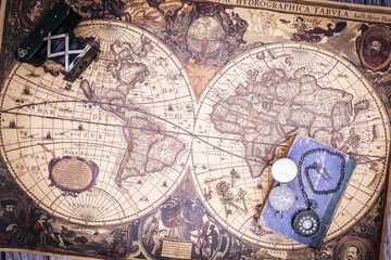 Fototapeta na wymiar zenithal view of still life composed of old books, pistols, pen with ink, camera and clock on a background of a classic map.