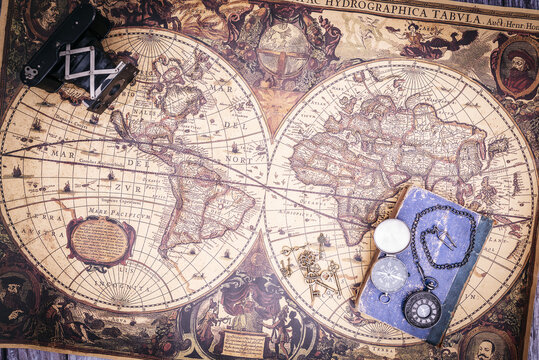 zenithal view of still life composed of old books, pistols, pen with ink, camera and clock on a background of a classic map.