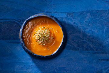 Pumpkin cream with germinated seeds on blue background