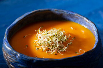 Pumpkin cream with germinated seeds on blue background