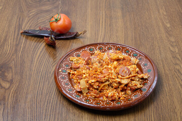 Mexican breakfast of egg and sausage in sauce along with tomato and chili peppers. Mexican food