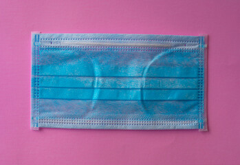 Single medical blue protective mask on a pink background