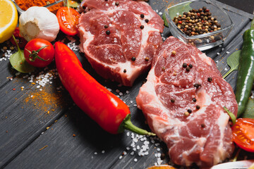 Raw pork meat on wooden cutting board at kitchen table for cooking pork steak roasted or grilled with ingredients herb and spices , Fresh pork
