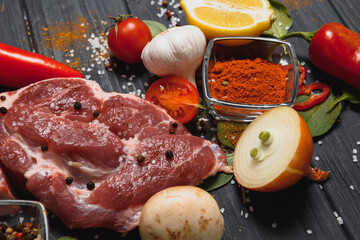 Raw pork meat on wooden cutting board at kitchen table for cooking pork steak roasted or grilled with ingredients herb and spices , Fresh pork