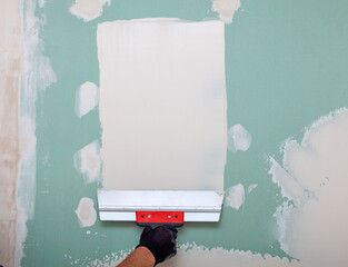 Hand of builder worker plastering at wall