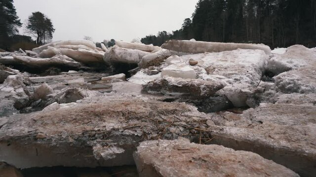 Huge Ice Loads Drift in the River Ogre, Latvia. Stedicam Shot in Snowy Mart Day. Congestion on the River in the Spring. A Large Cluster of Moving Ice Blocks
