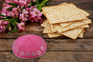 Jewish matzah bread with kippah and flowers on wooden background. Passover holiday concept.