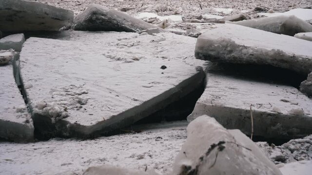 Huge Ice Loads Drift in the River Ogre, Latvia. Stedicam Shot in Snowy Mart Day. Congestion on the River in the Spring. A Large Cluster of Moving Ice Blocks
