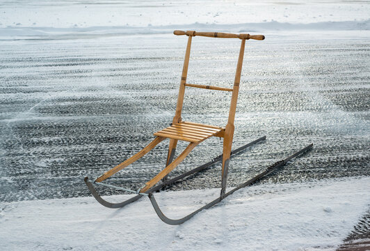 Kick-sledge parked on ice of a lake in winter sun