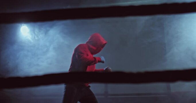 Portrait, boxer practicing punches in the ring, dark gym with tubers of smoke. Shadow boxing, professional boxing trainer. 4k, ProRes
