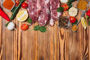 Raw pork meat with spices and vegetables on wooden table