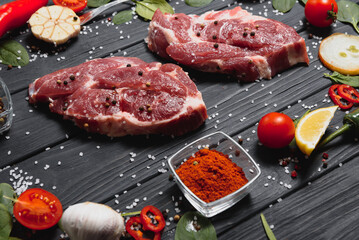 Raw pork meat on wooden cutting board at kitchen table for cooking pork steak roasted or grilled with ingredients herb and spices , Fresh pork