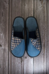 Dos zapatillas de hombre fabricadas con tela de color azul  sobre suelo de madera.