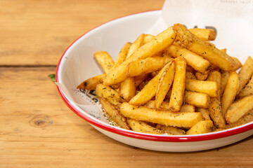 Chips with rosemary, in a shallow bowl on wooden table